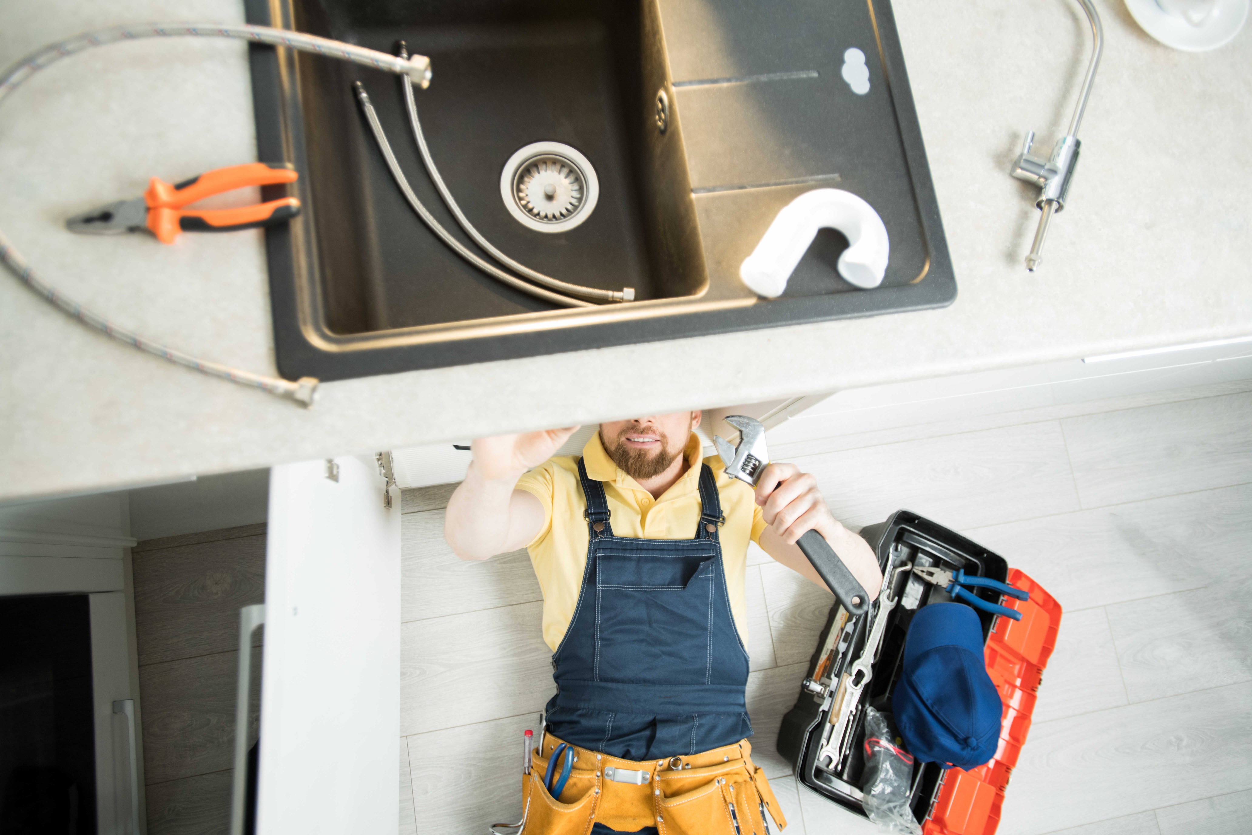 Plumber repairing kitchen plumbing